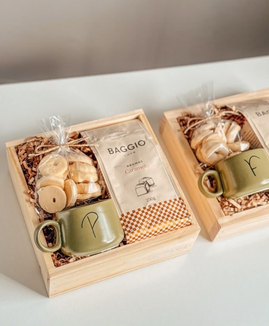 Caixa de madeira com café, biscoitos e caneca verde com inicial