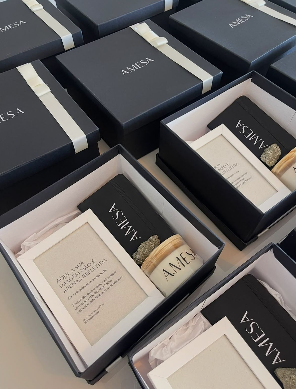 Caixas pretas com marca de cliente, vela, caderno e porta-retrato